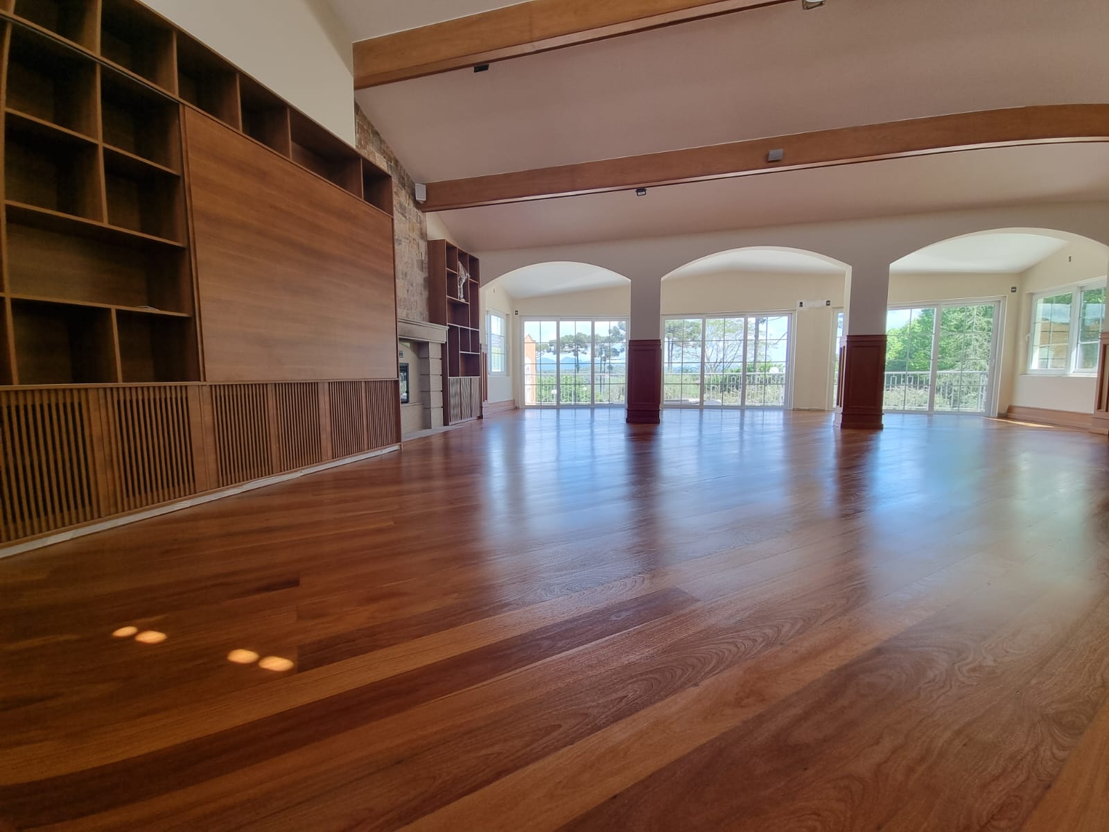 Salão amplo com piso de madeira restaurado, ângulo alternativo